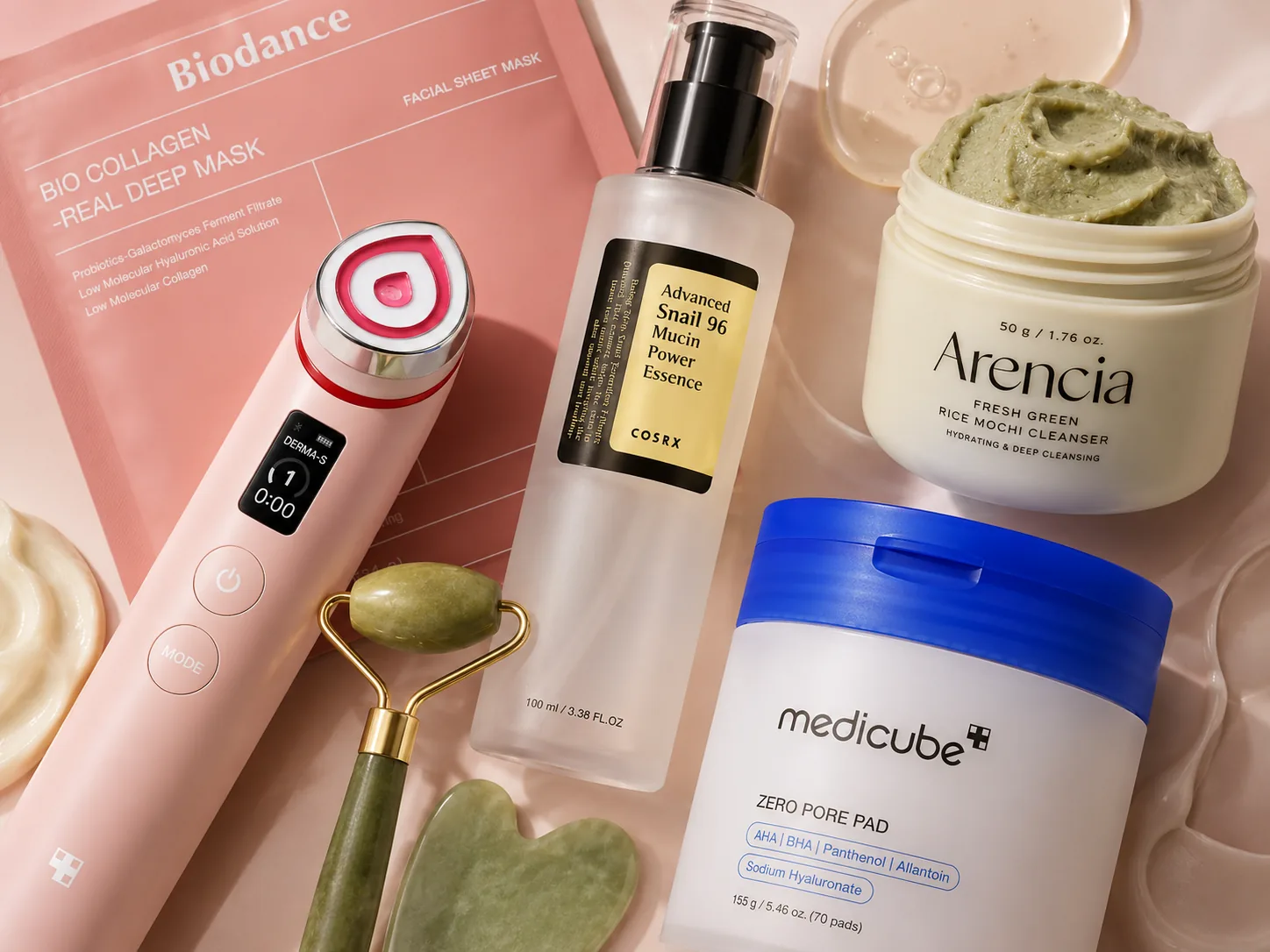 A flat-lay of top-rated skincare products — Biodance collagen mask, jade roller and gua sha, COSRX snail mucin essence, Arencia rice mochi cleanser and medicube zero pore pads